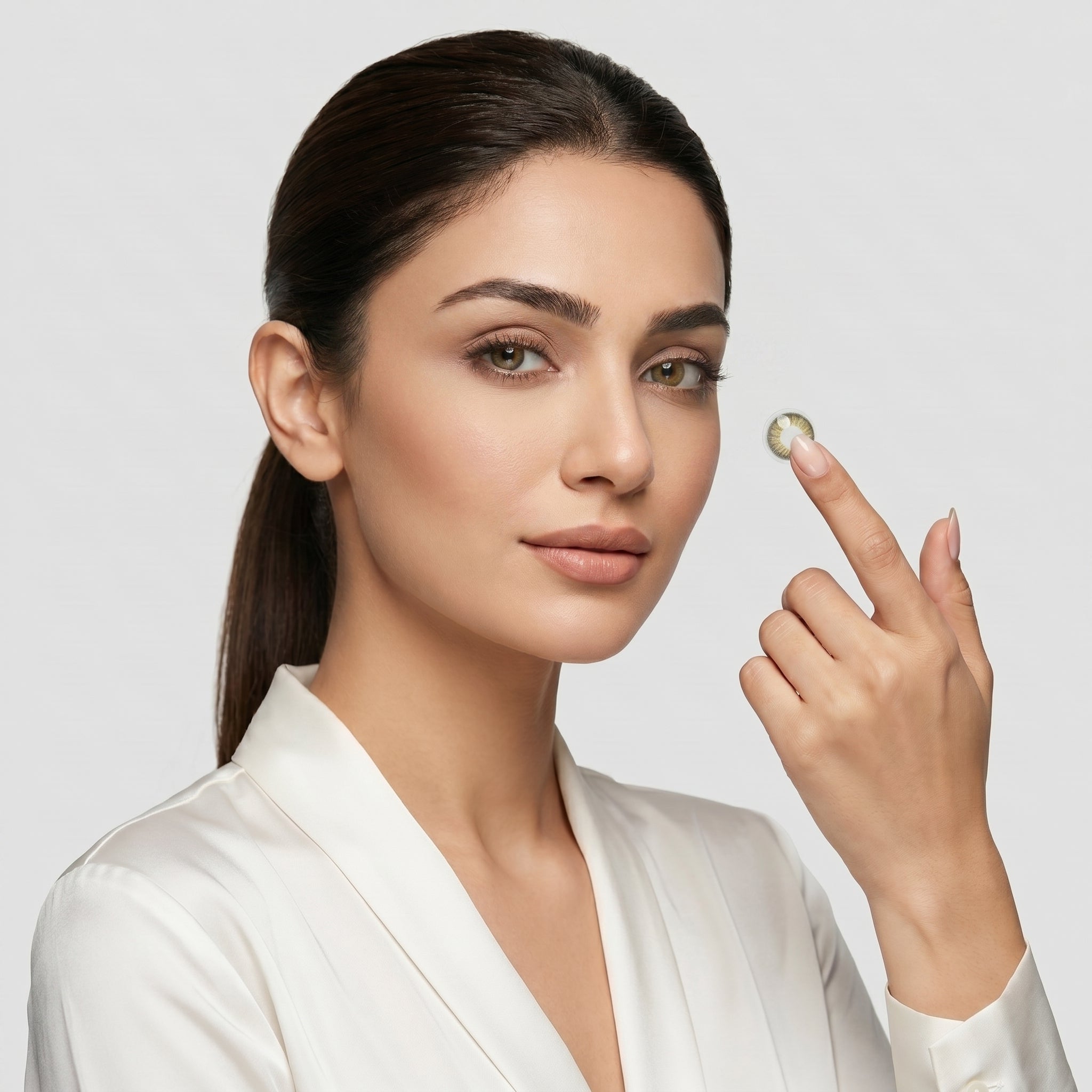 Woman holding a diamond between her fingers against a plain background